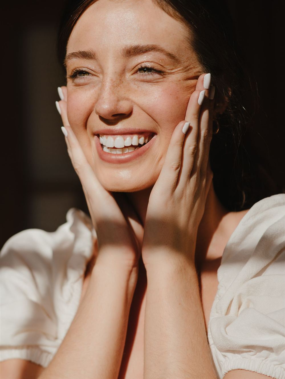 Mulher sorrindo com as mãos no rosto