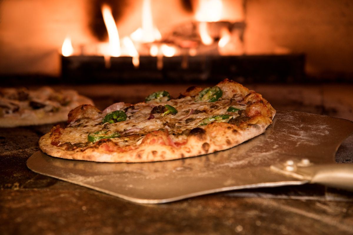 Pizza saindo do forno a lenha